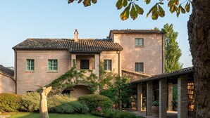 A two-story building with a brick facade, a tiled roof, and a small arched entrance. - Tenuta Santi Giacomo e Filippo (Urbino)