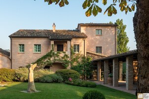 A two-story building with a brick facade, a tiled roof, and a small arched entrance.