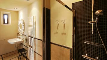 Un baño con lavamanos, espejo, toallero y ducha con puerta de vidrio.