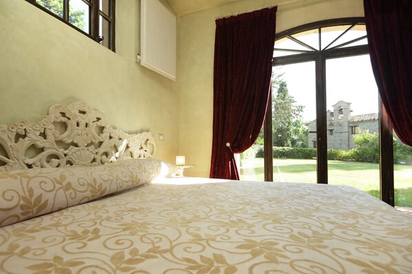 Une chambre à coucher avec un grand lit, une table de chevet et une fenêtre avec des rideaux.