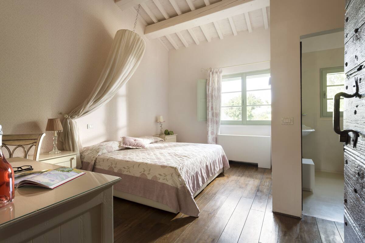 Une chambre à coucher avec un lit, une table de chevet, une lampe et une fenêtre avec des rideaux.