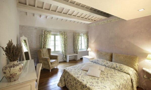 A bedroom with a bed, a chair, a desk, a lamp, and a vase. - Tenuta Santi Giacomo e Filippo (Urbino)