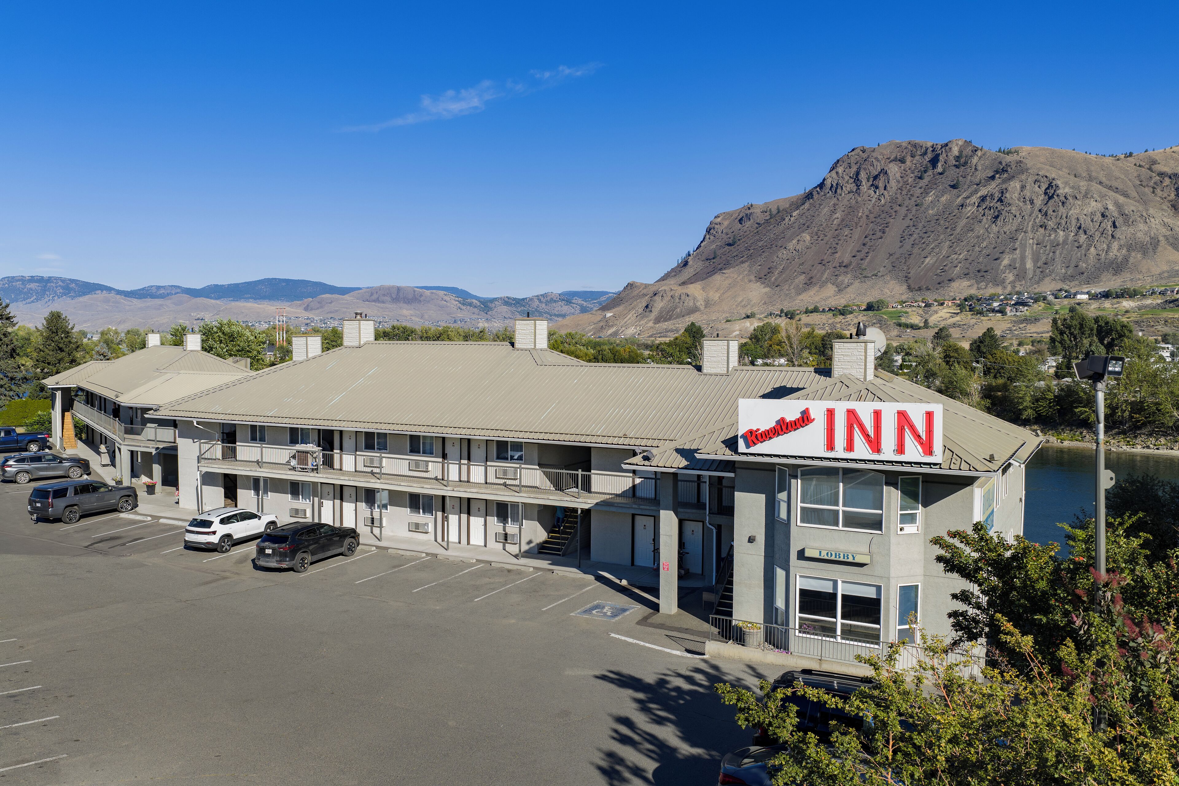 A motel with a sign reading "Inn" and a parking lot with several cars.