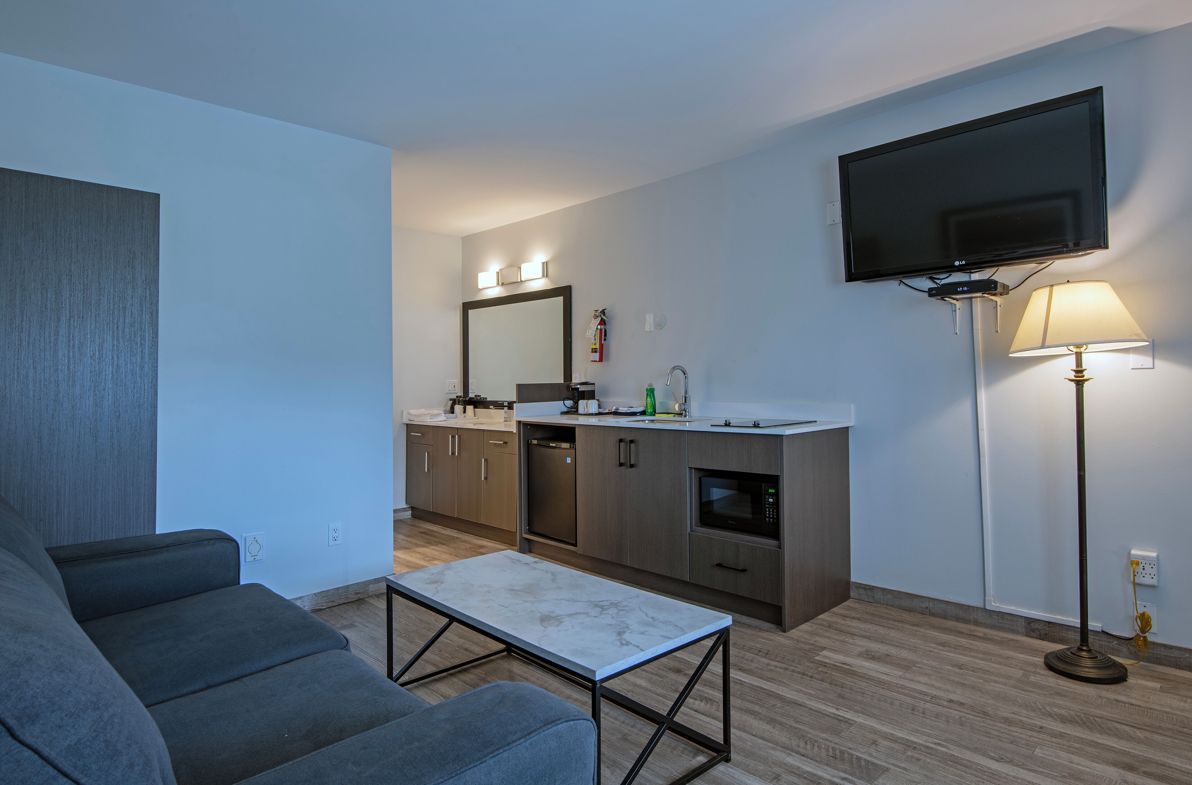 A modern kitchen with a flat-screen TV, a dining area with a table, and a sofa.