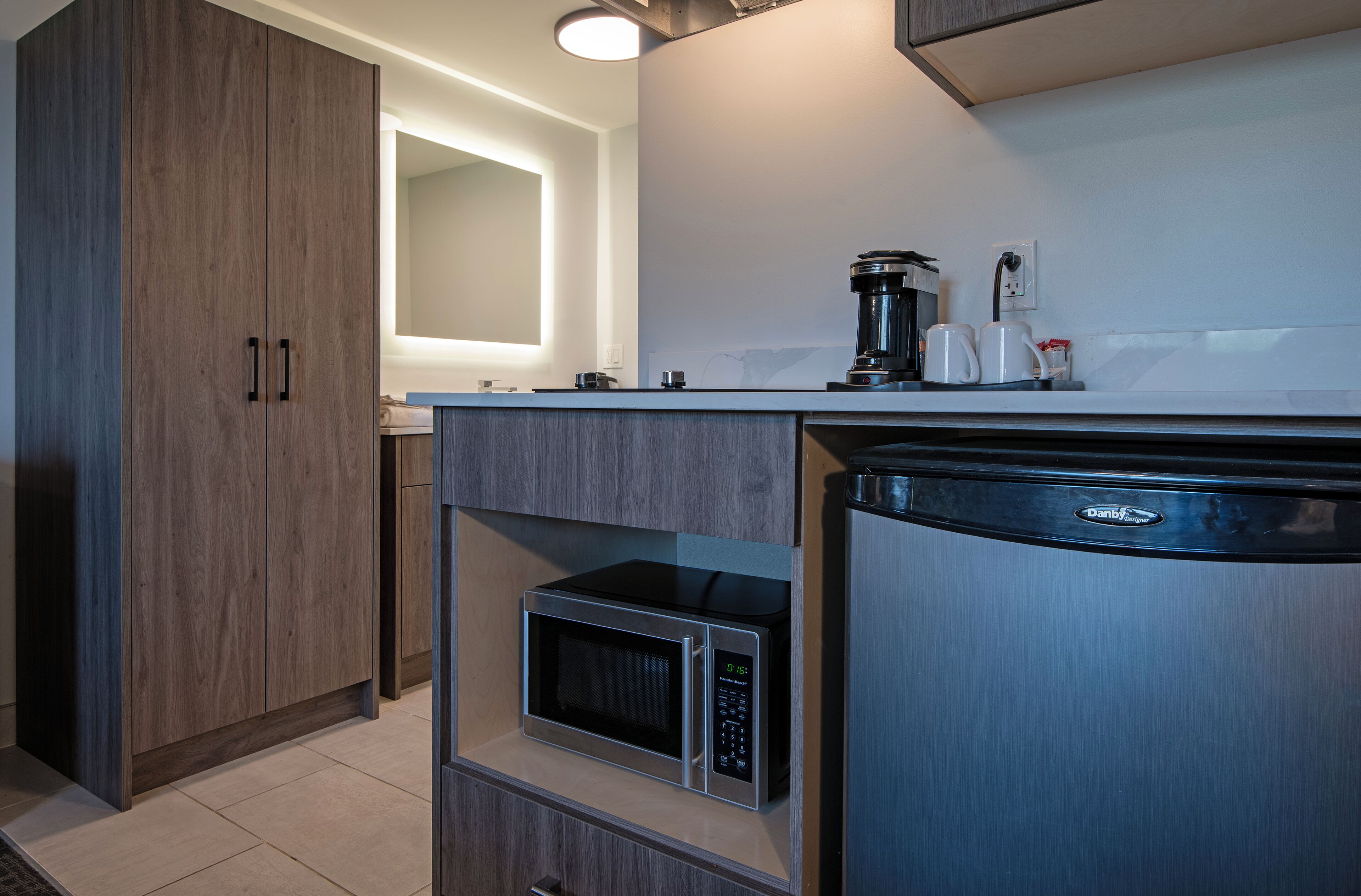 A modern kitchen with built-in appliances, including a microwave and coffee maker, and wooden cabinets.