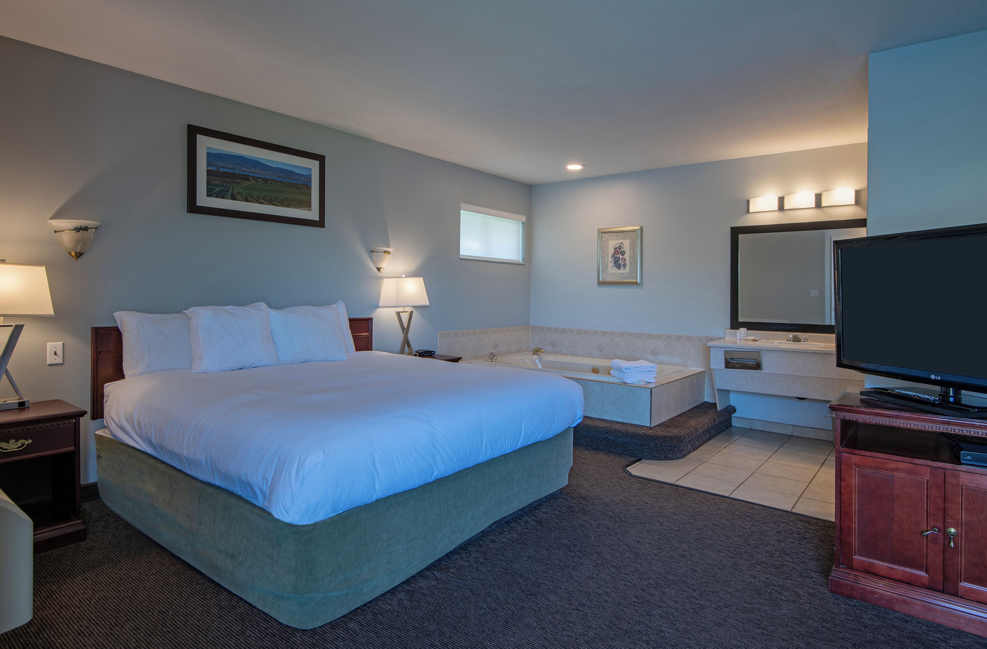 Una habitación de hotel con una cama grande, un sofá, una televisión, un baño y un escritorio.