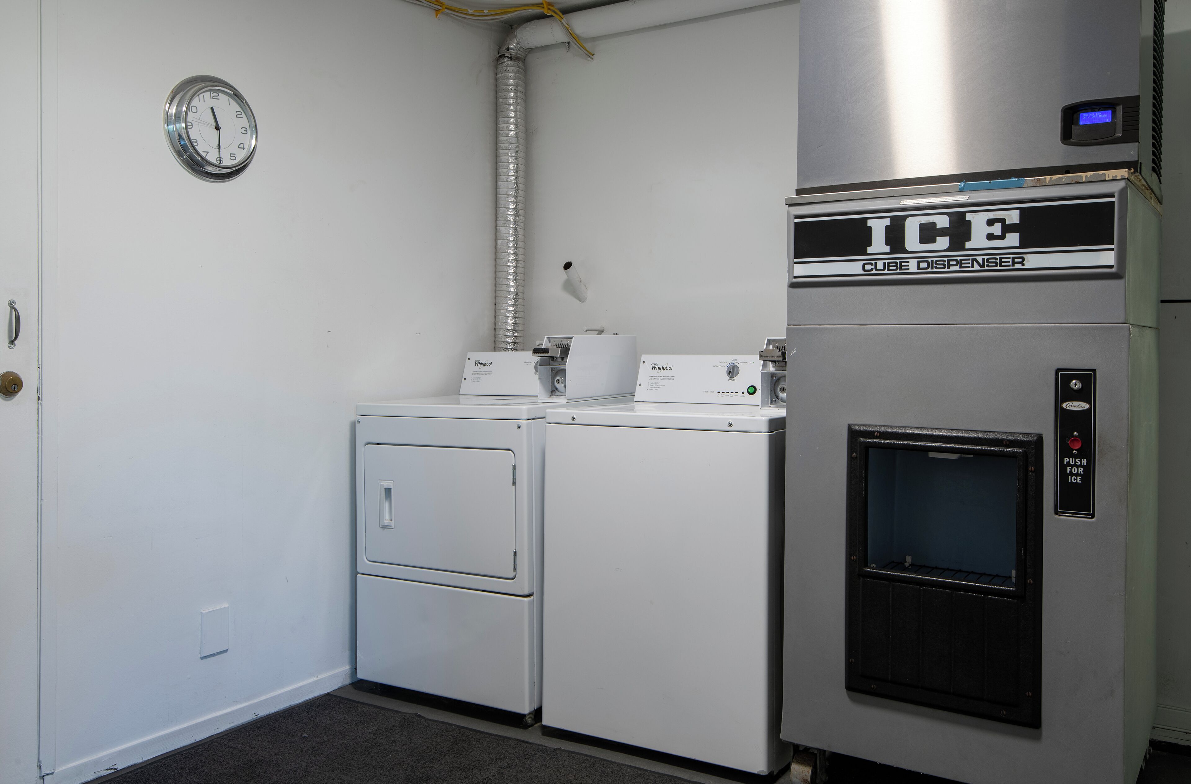 Een wasserette met een Whirlpool wasmachine, een Whirlpool droger en een ijsblokjesmachine.