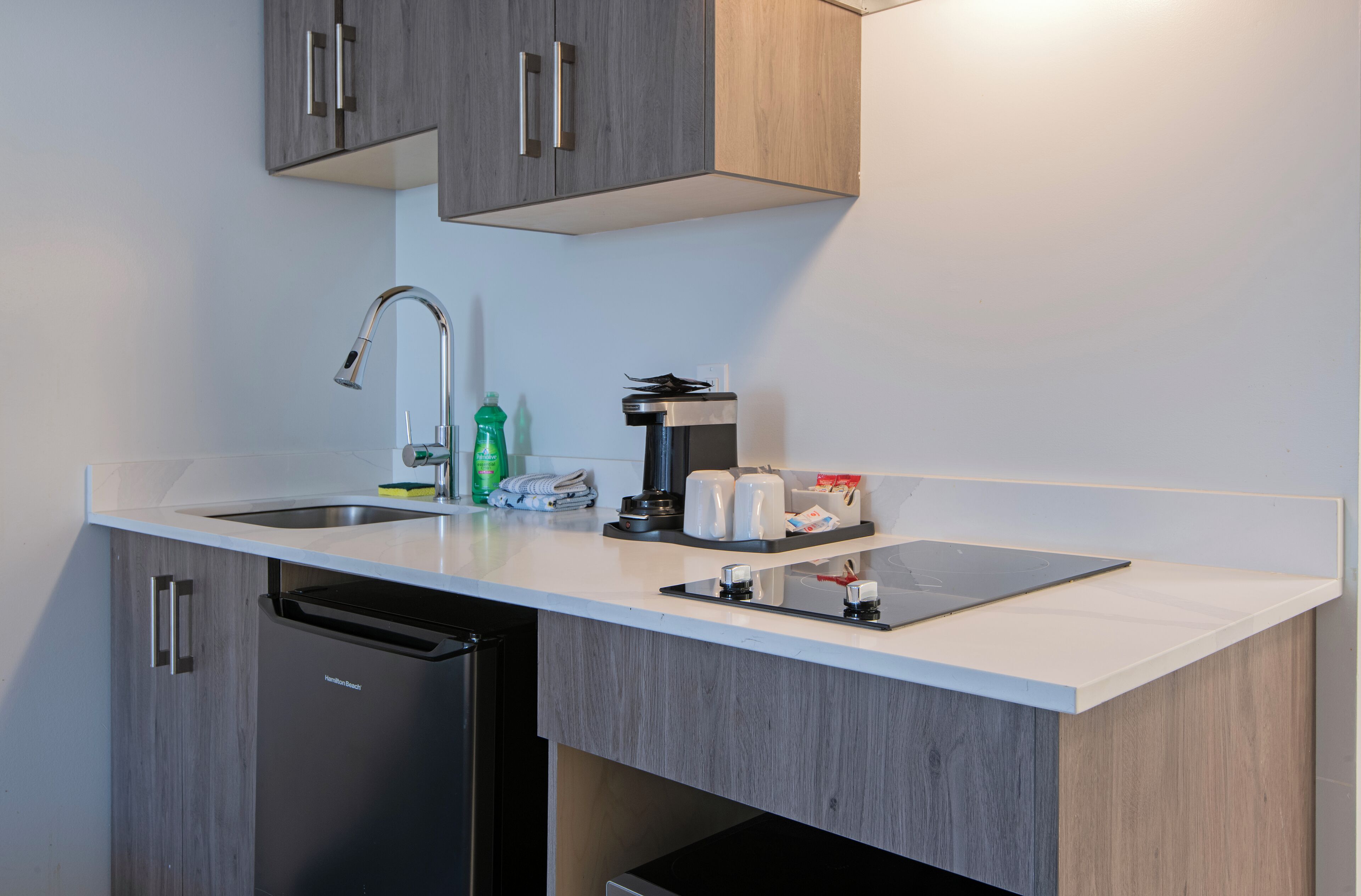 A modern kitchen with a dishwasher, a coffee machine, and a sink.