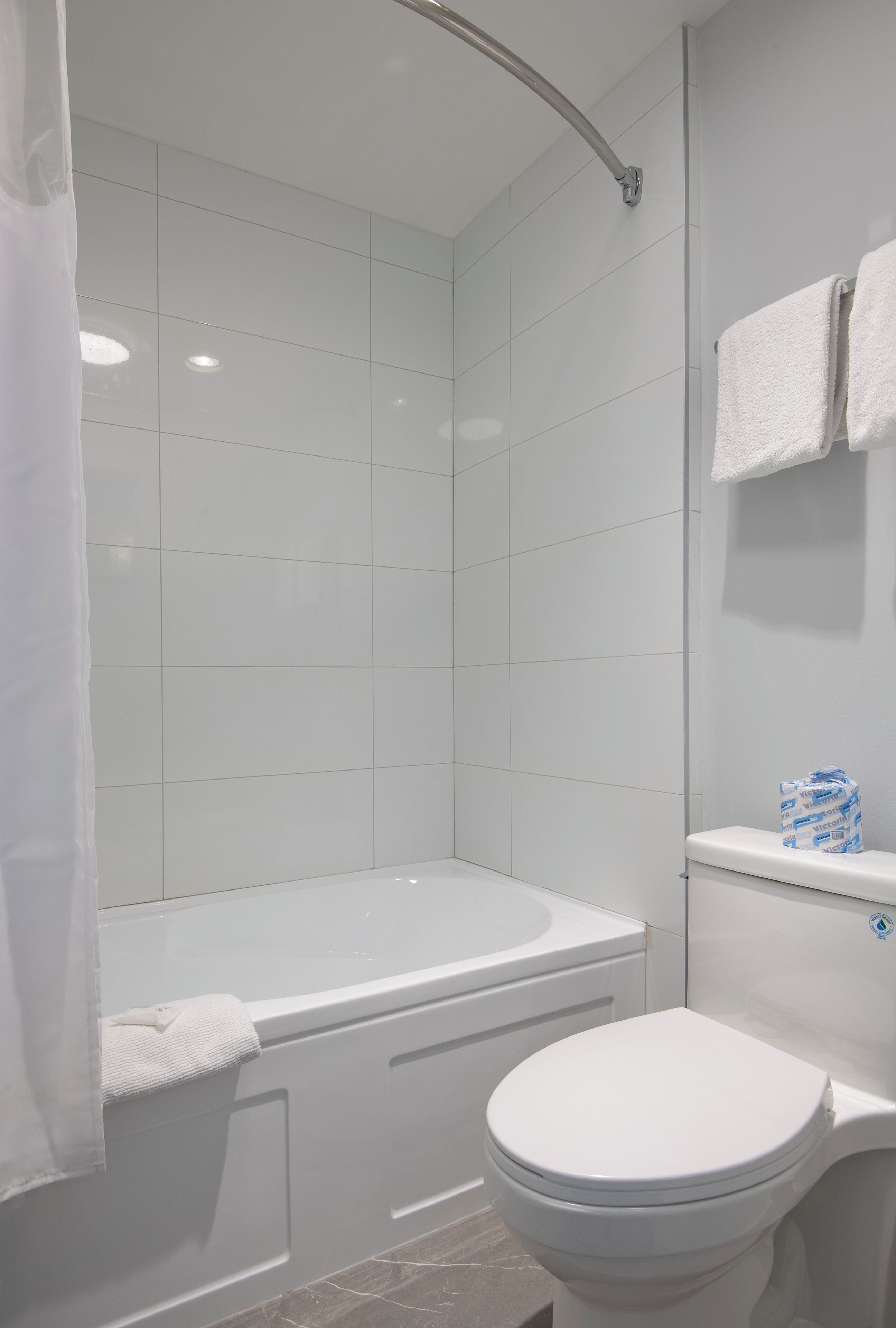 A bathroom with a bathtub, toilet, and shower curtain.
