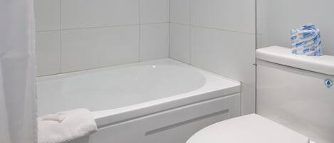 A bathroom with a bathtub, toilet, and shower curtain.