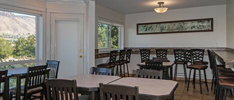 A dining area with multiple tables and chairs, a view of a mountain, and a framed artwork on the wall.
