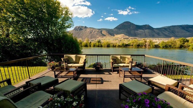 Un patio con mobiliario exterior y vistas a un río y montañas.