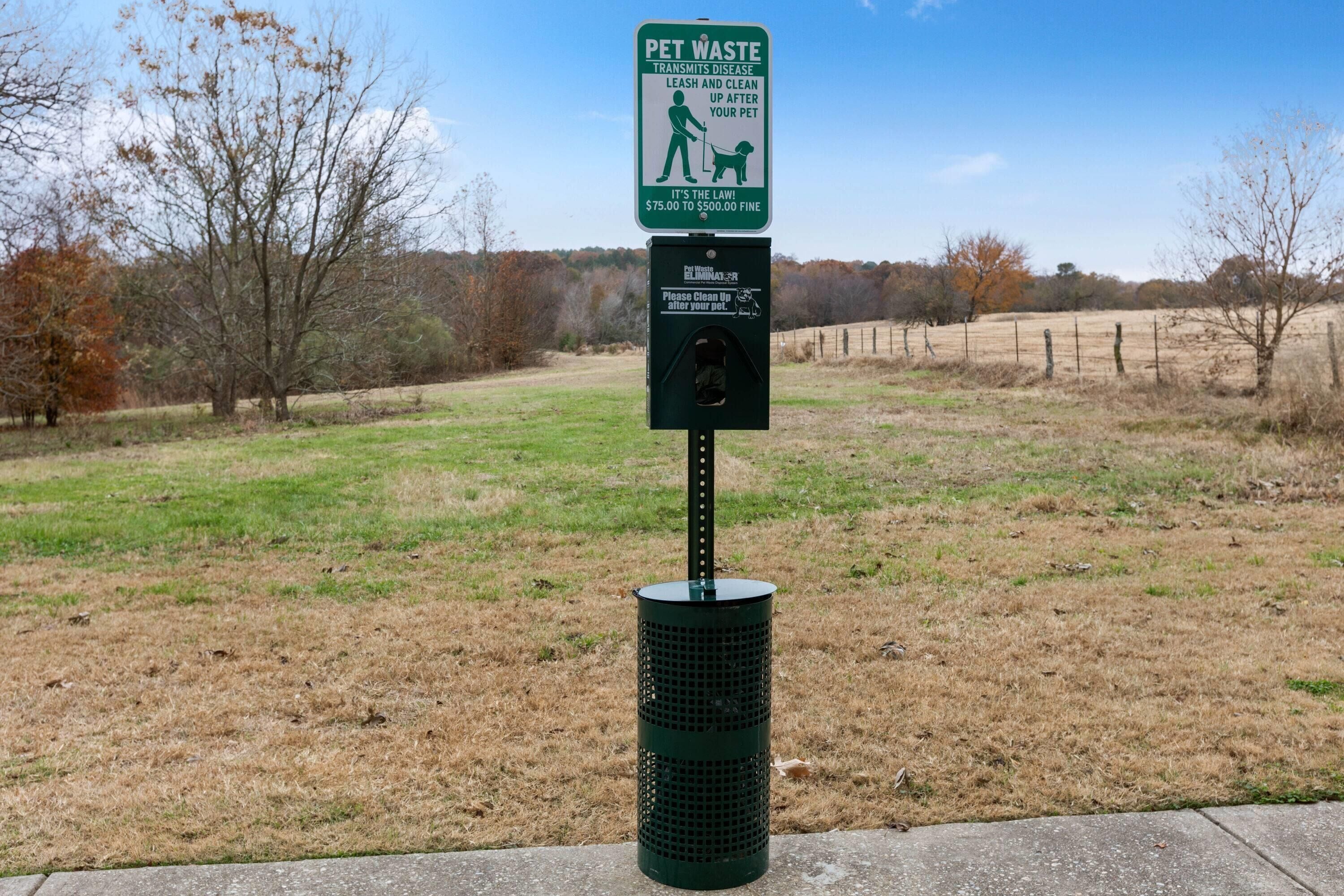 A pet waste station with a sign and a trash can.