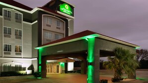 Ein Hotel mit auffälliger Beschilderung, überdachter Eingangsparte und einer Palme.