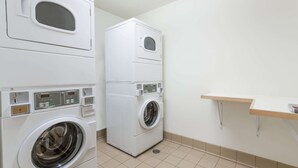 A laundry room with two stacked washing machines and a small shelf. - Super 8 by Wyndham Alma (Alma)