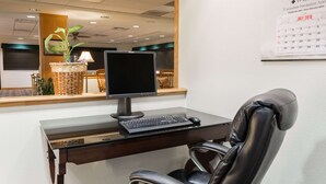 A reception desk with a computer, a chair, a lamp, and a calendar on the wall. - Super 8 by Wyndham Alma (Alma)