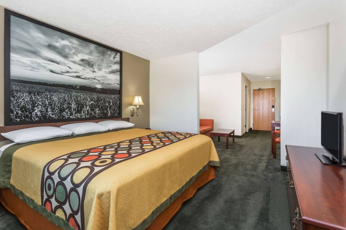 A hotel room with a large bed, a flat-screen TV, a desk, and a chair.