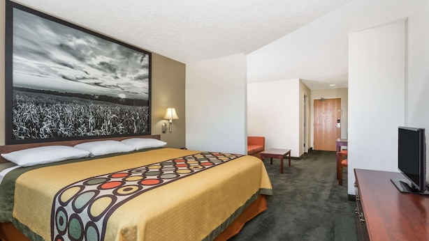 A hotel room with a large bed, a flat-screen TV, a desk, and a chair. - Super 8 by Wyndham Alma (Alma)