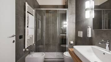 A modern bathroom with a glass-enclosed shower, a standalone sink, and a toilet.