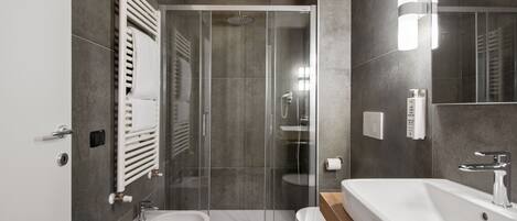 Un baño moderno con ducha de vidrio, lavamanos independiente y un inodoro.