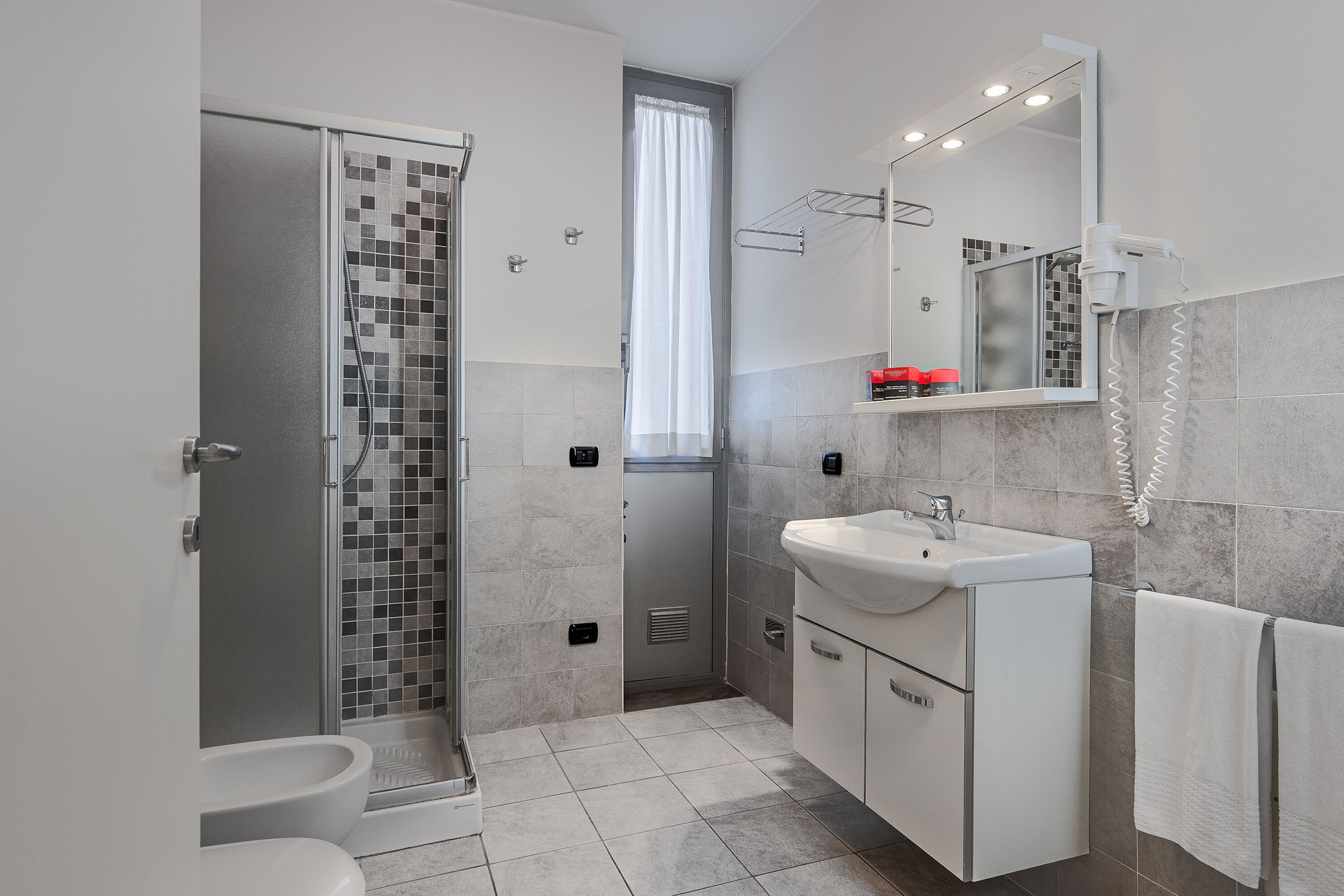 Een moderne badkamer met douche, toilet en wastafel.