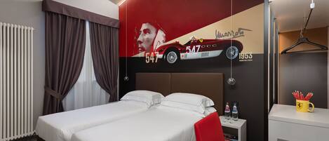 A hotel room with a bed, a red chair, a small table with bottles, and a wall with a car and numbers.