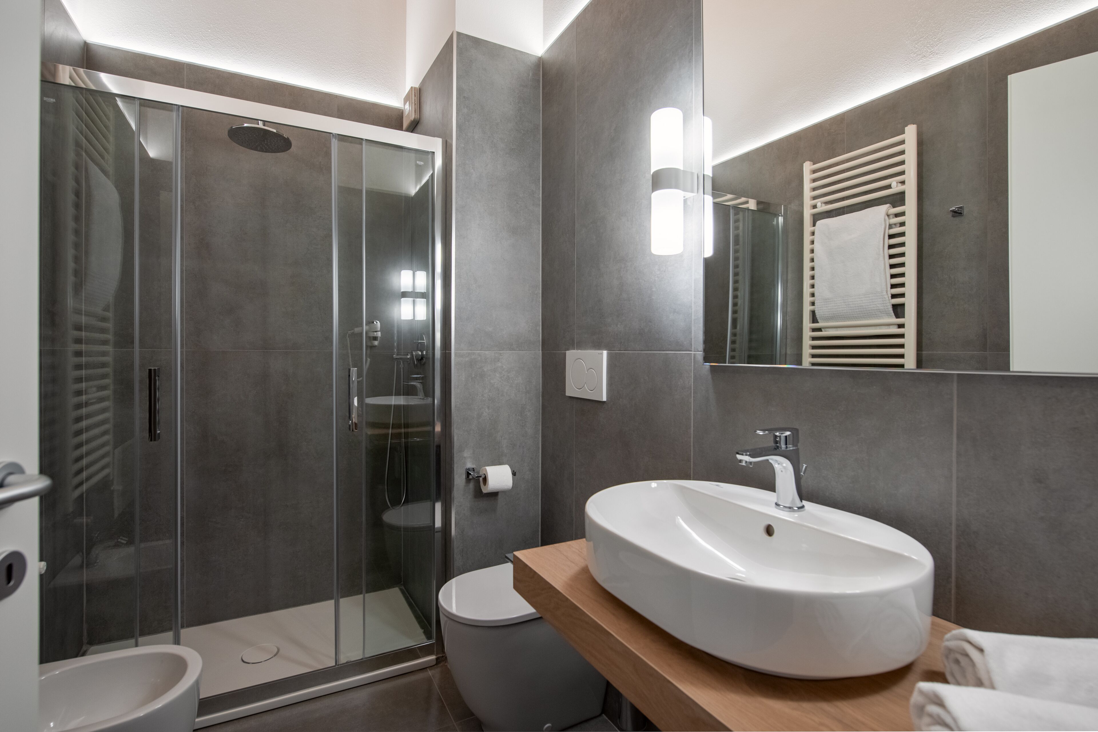 Une salle de bain moderne avec une douche à parois de verre, un lavabo blanc et un meuble-lavabo en bois.