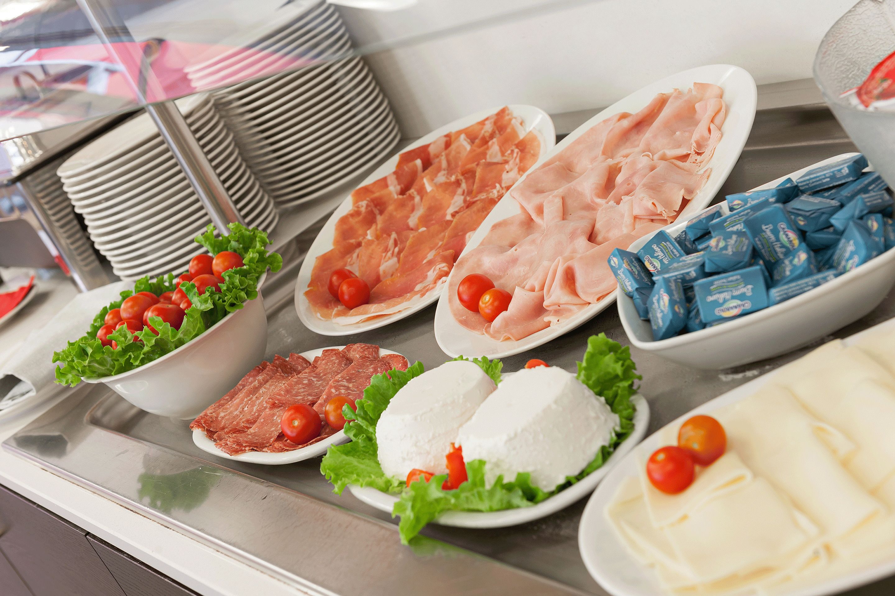 A buffet with various food items including meats, cheeses, and vegetables.