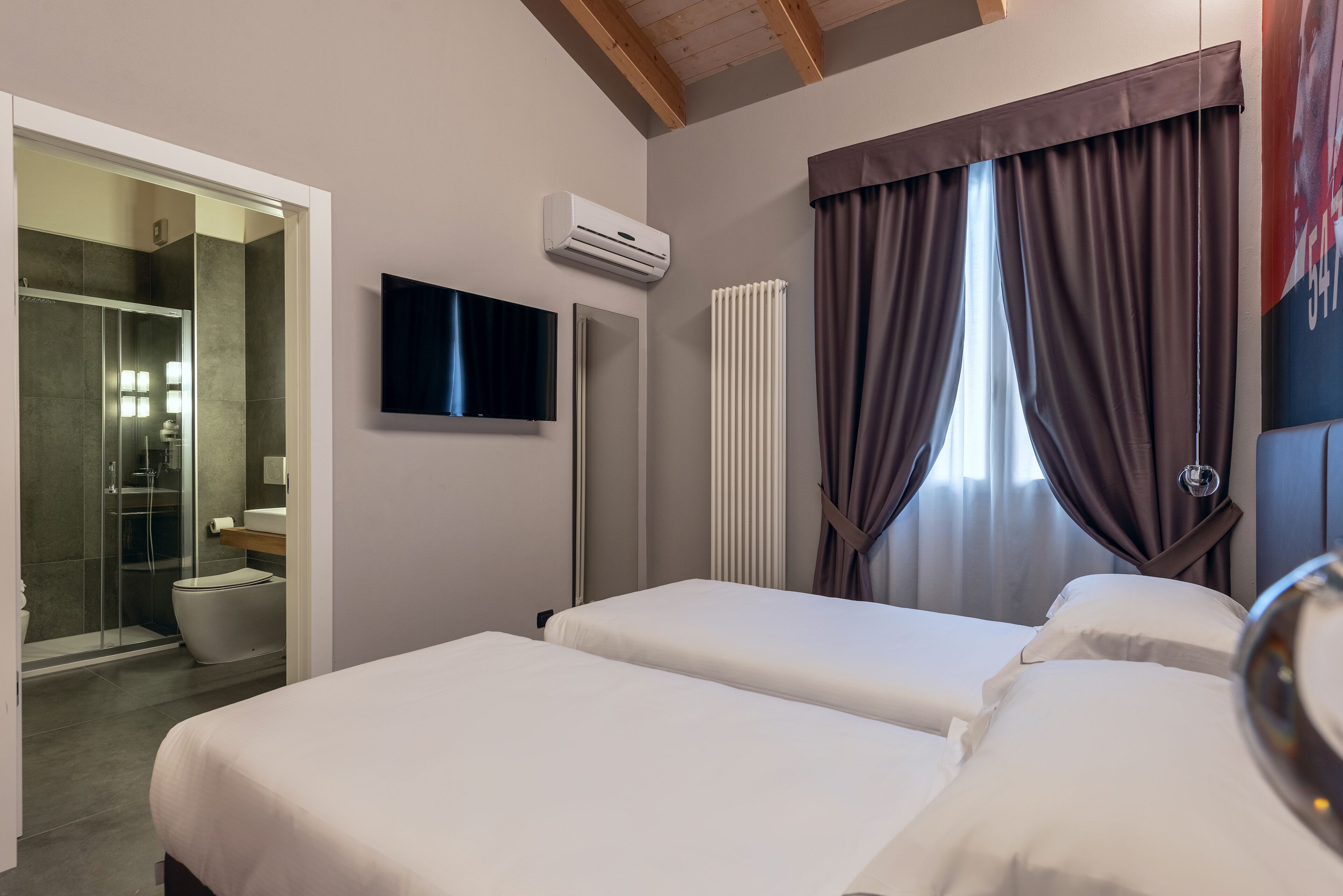 Habitación de hotel con dos camas, televisión, ducha y retrete.