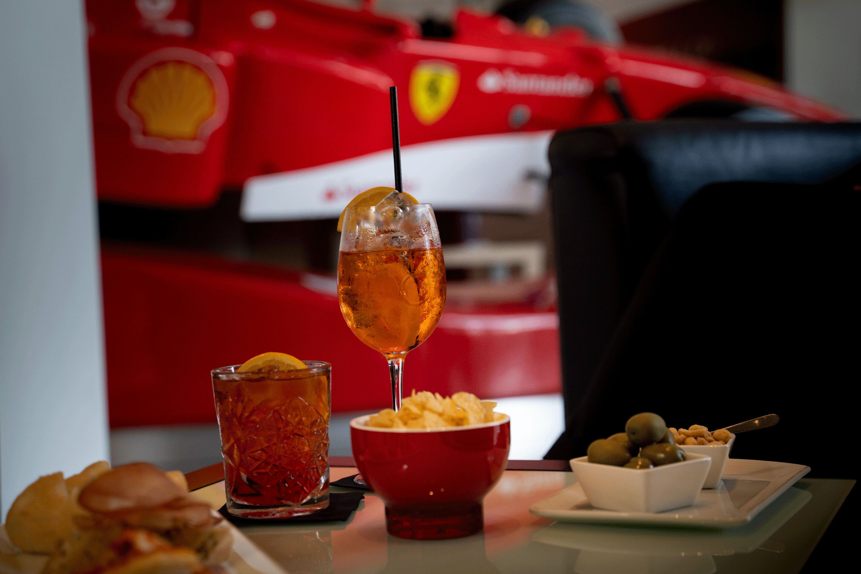 Une table avec une boisson, un bol de chips et une assiette d’olives et de noix.