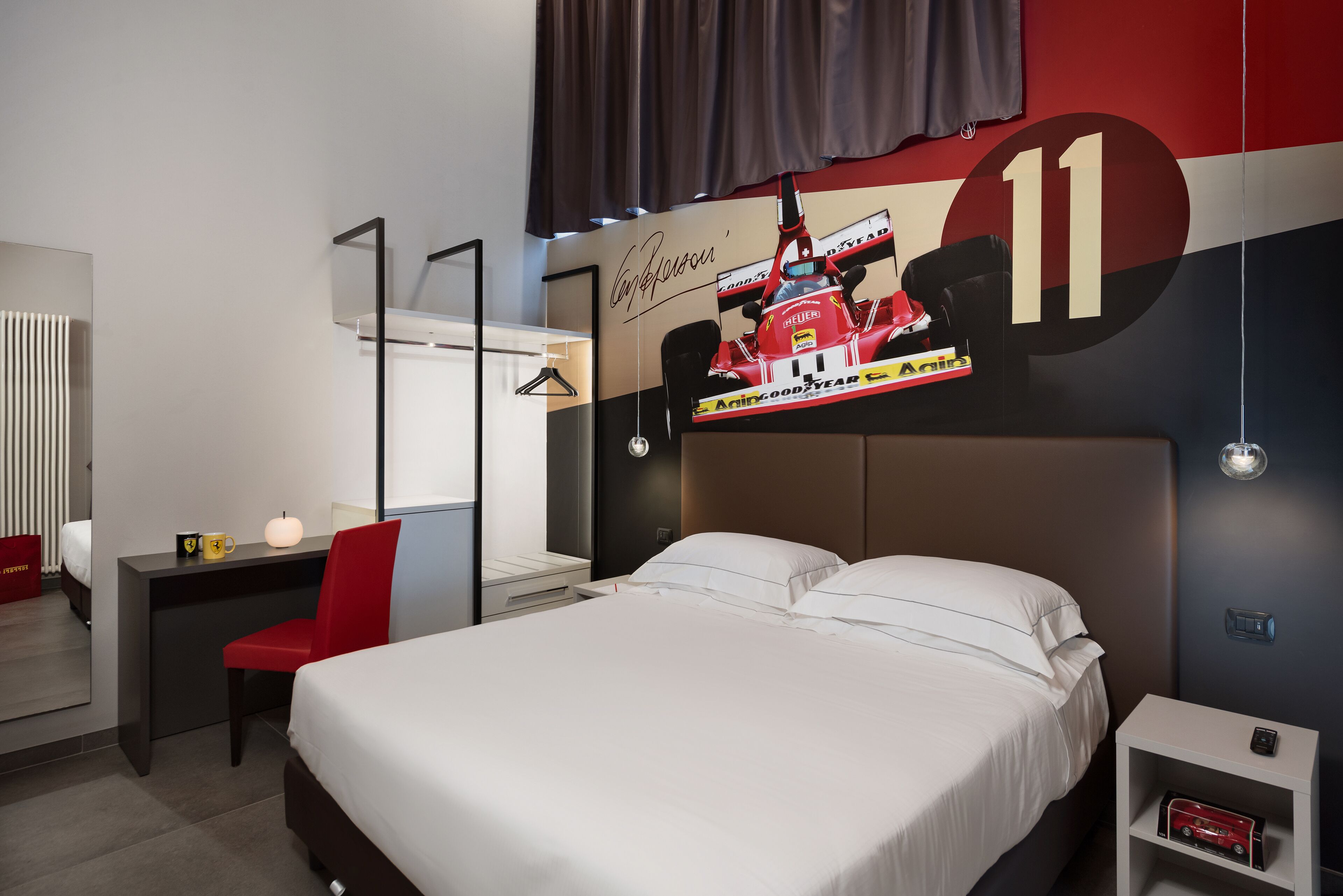 A hotel room with a bed, a desk, a chair, a TV screen, and a wall with a large number '11'.