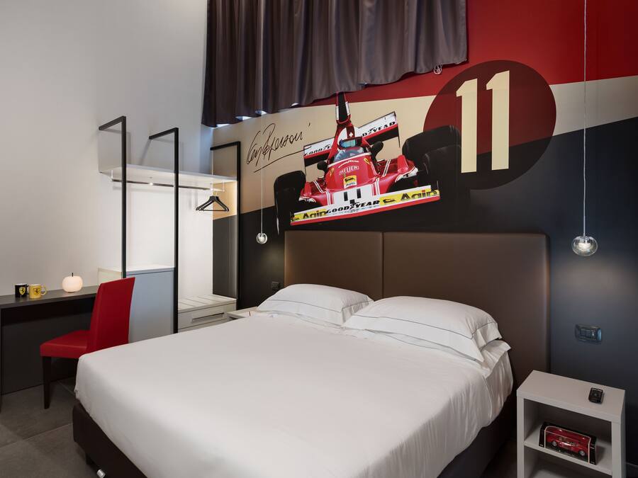 A hotel room with a bed, a desk, a chair, a TV screen, and a wall with a large number '11'.
