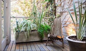 Una terraza de madera con plantas en macetas y una silla de madera.