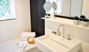 Un baño moderno con un lavamanos grande, dos espejos, una toalla y una planta pequeña.