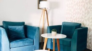 A room with two teal sofas, a small white table, and a floor lamp.