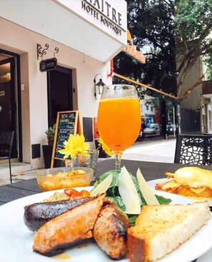 Un restaurante con un letrero que dice 'Hôtel Boutique' y un vaso de jugo de naranja sobre la mesa.