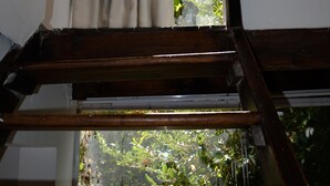 A staircase leading to a window with curtains and a view of greenery outside.