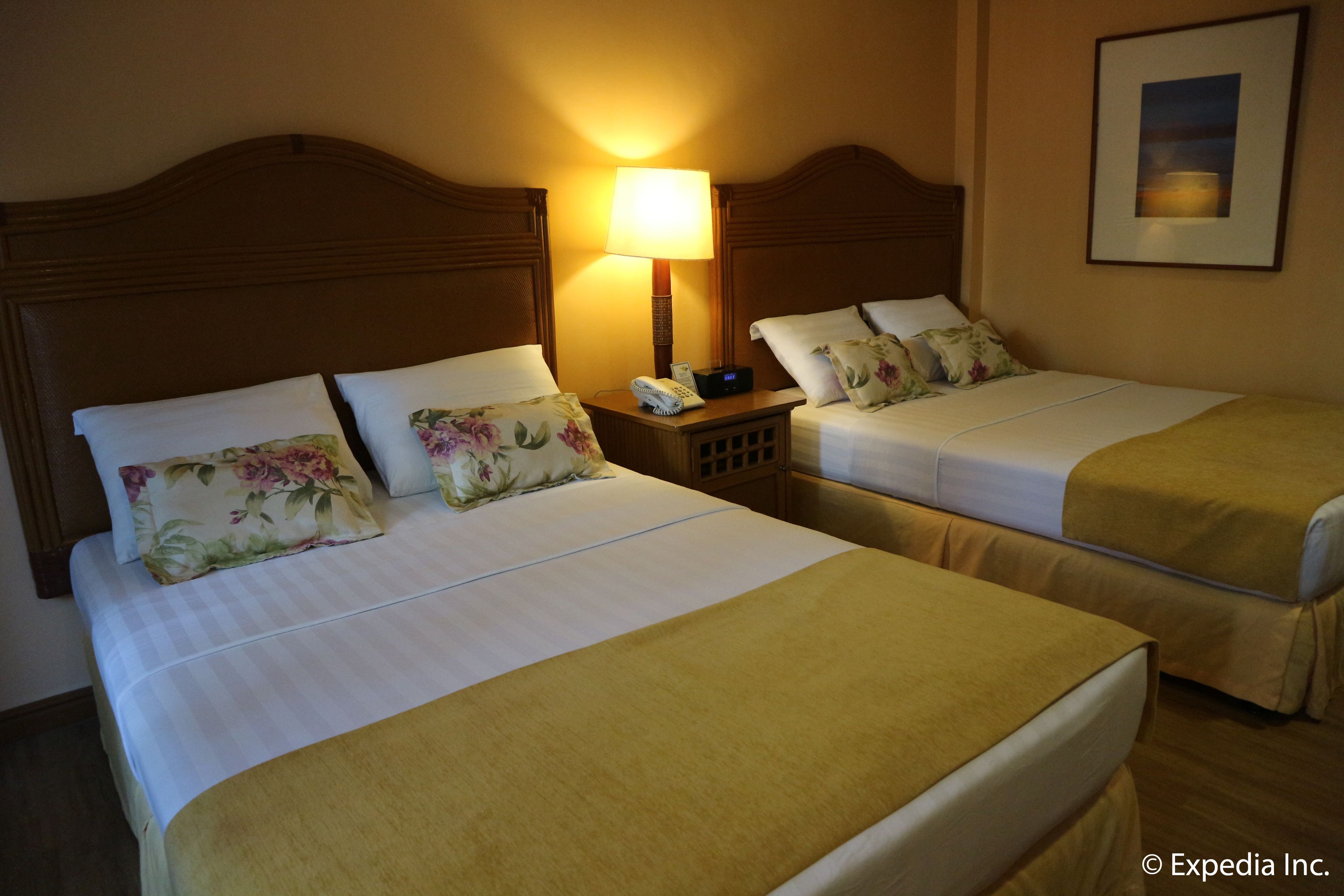 Two single beds with floral bedding, a bedside table with a lamp, and a framed picture on the wall.