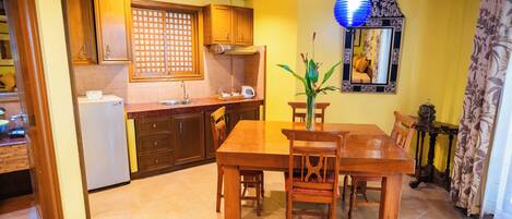 A dining area with a wooden table and chairs, a refrigerator, wooden cabinets, and a decorative mirror.