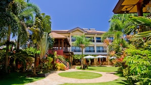A hotel courtyard with a central lawn, palm trees, and outdoor seating areas. - Boracay Tropics Resort Hotel (Boracay Island)