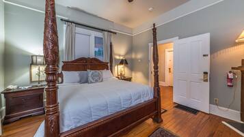 A four-poster bed with a wooden headboard, a bedside table with a lamp, and a nightstand with a phone.
