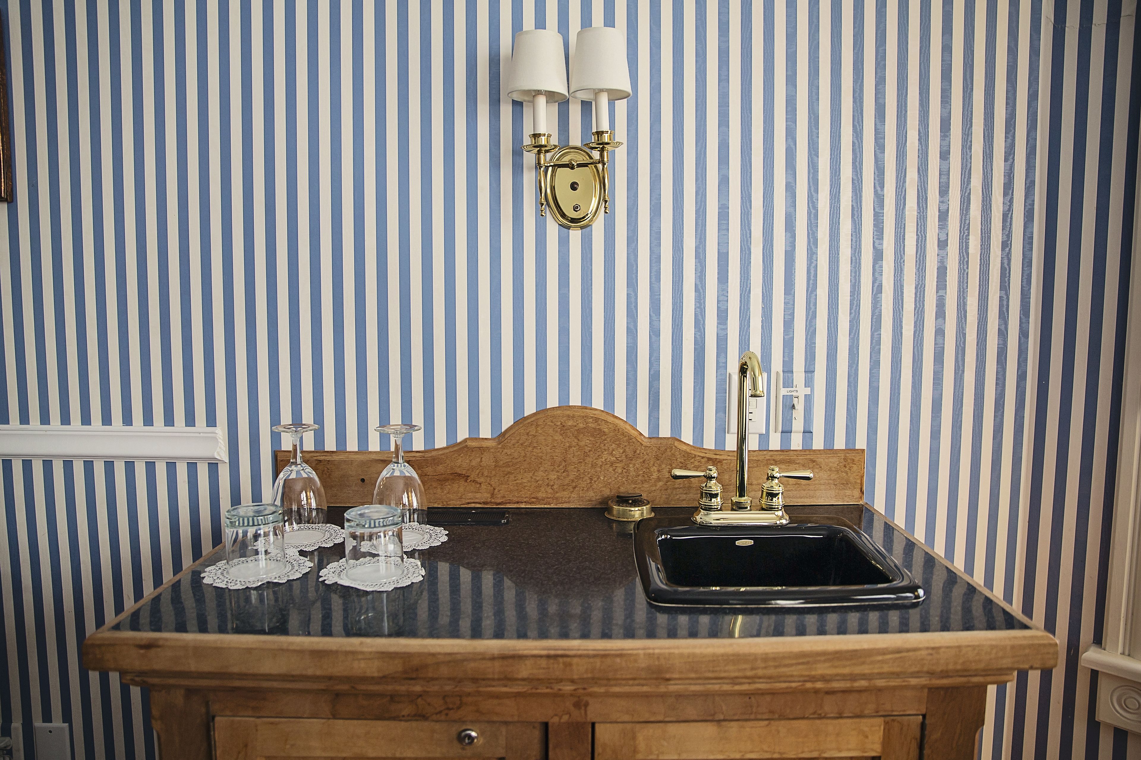 A bathroom with a wooden vanity, a black sink, and a wall-mounted light fixture.