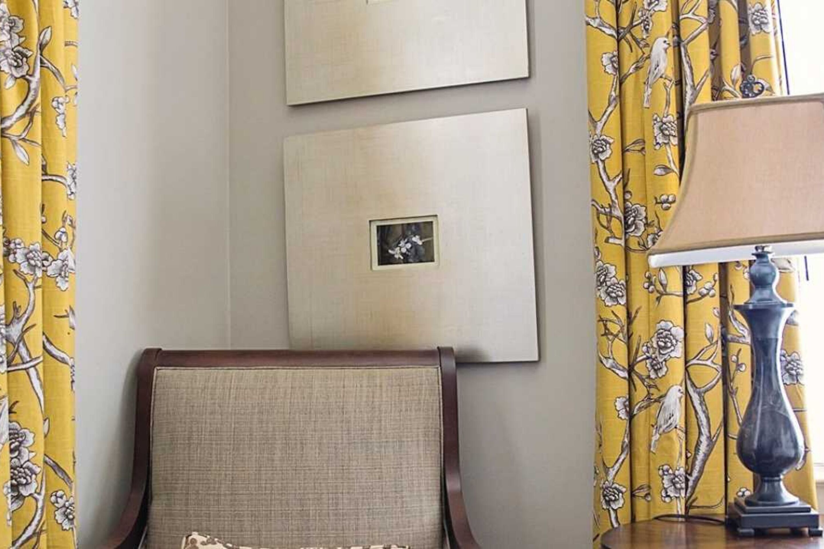 Une pièce avec une chaise, une lampe et trois tableaux encadrés accrochés au mur.