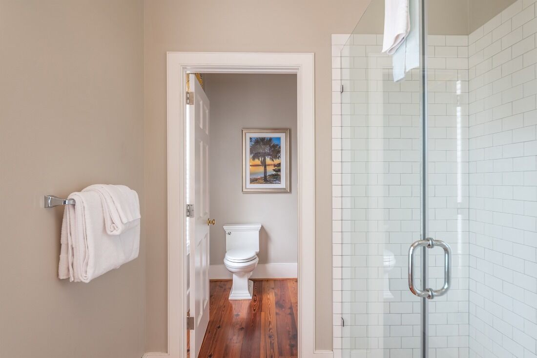 Et badeværelse med toilet, glas brusekabine og håndklædestang.