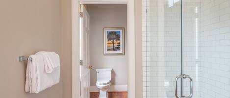 Un baño con inodoro, cabina de ducha de vidrio y perchero para toallas.