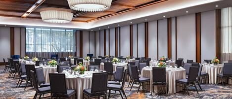 A conference room with round tables, chairs, and a patterned carpet.
