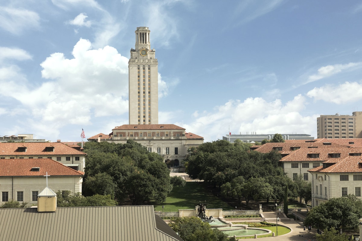 A large institutional building with a prominent clock tower, surrounded by trees and other buildings.