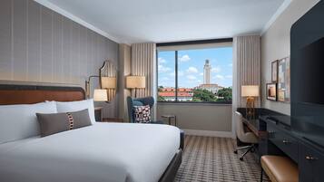 Habitación de hotel con una cama grande, un escritorio, una silla y vista a un paisaje urbano.