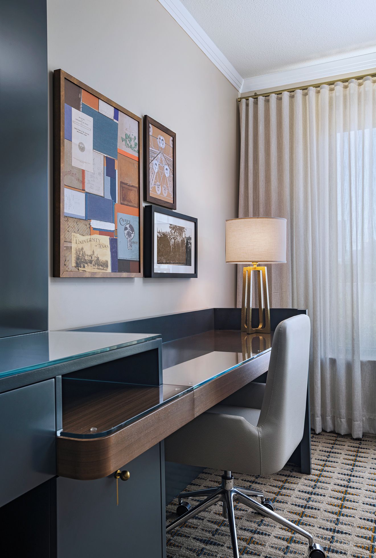 A hotel room with a desk, a chair, a lamp, and a bulletin board with various items pinned to it.
