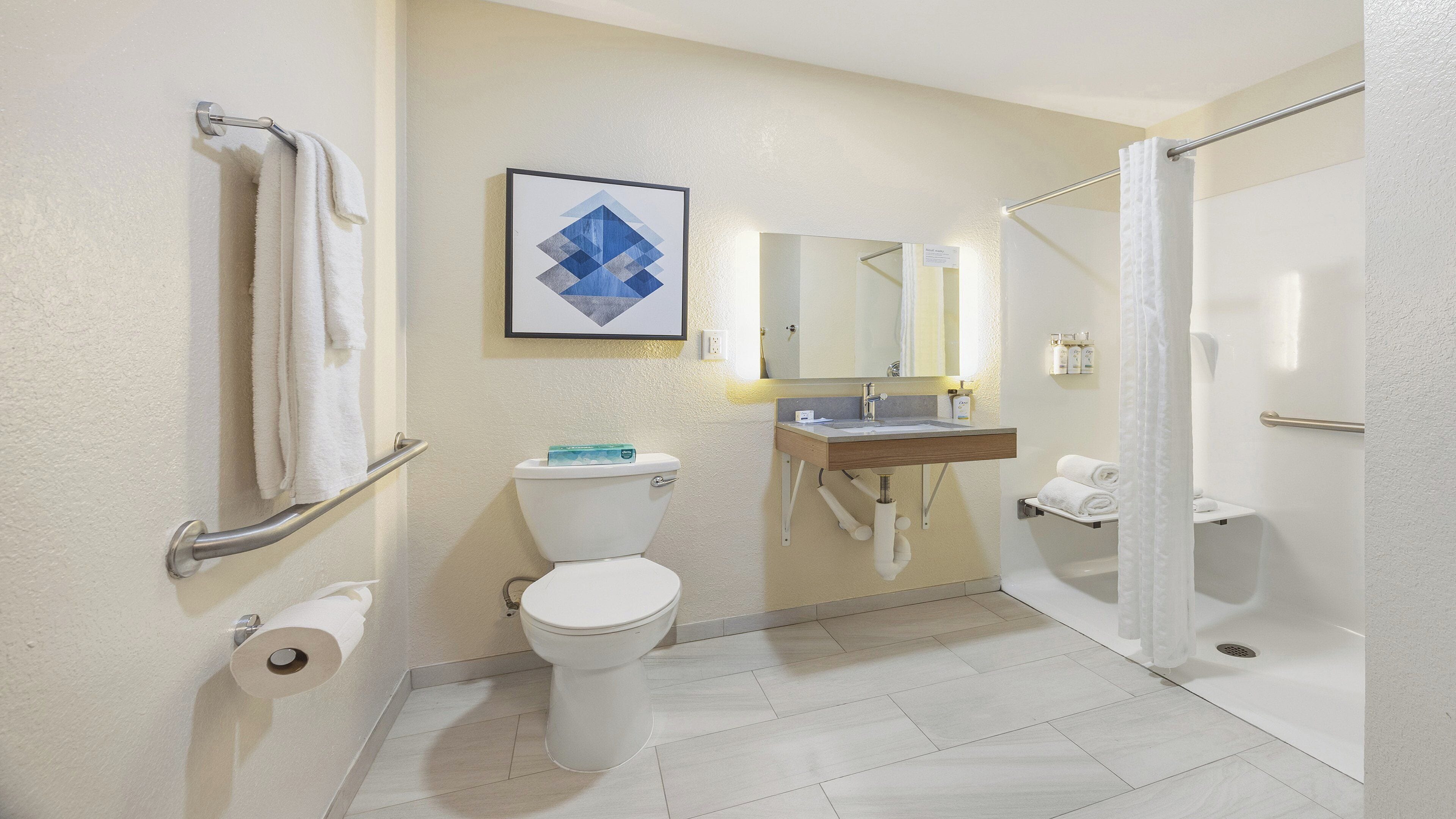 A bathroom with a toilet, sink, shower, and towel rack.